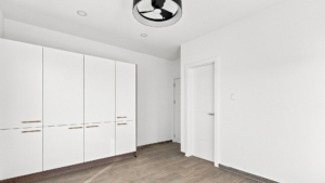 Reina Sophia Model Luca Unit 20 interior in Aruba with a wall of white built-in wardrobes, wood-toned handles, tiled flooring, and interior doors.