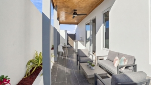 Furnished covered patio at Reina Sophia Model Luca Unit 20 in Aruba with gray outdoor seating, a coffee table, plants, tiled flooring, and a ceiling fan.