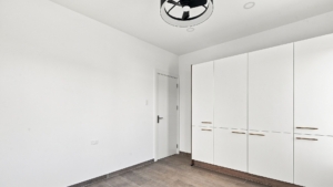 Reina Sophia Model Luca Unit 20 interior in Aruba with white built-in wardrobes, a doorway, tiled flooring, and white walls.