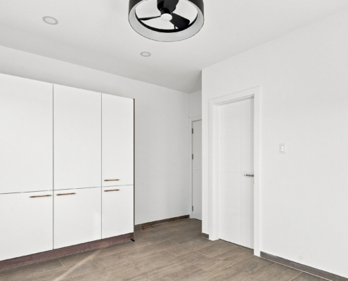 Reina Sophia Model Luca Unit 21 interior in Aruba with a wall of white built-in wardrobes, wood-toned handles, tiled flooring, and interior doors.