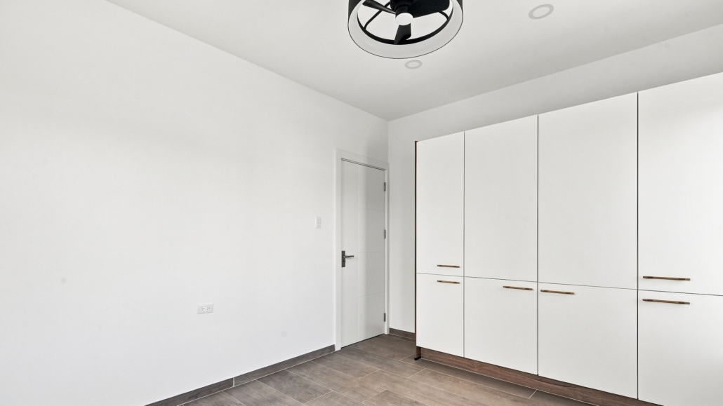 Reina Sophia Model Luca Unit 21 interior in Aruba with white built-in wardrobes, a doorway, tiled flooring, and white walls.