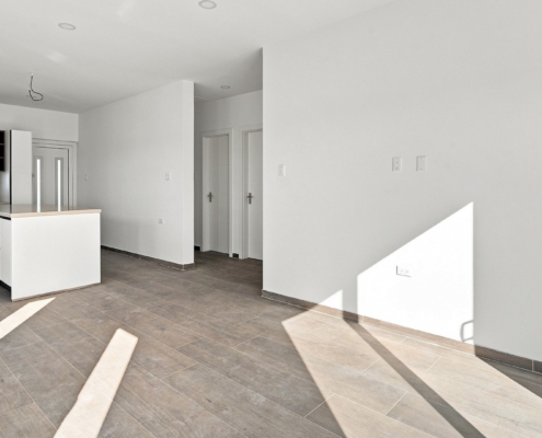 Reina Sophia Model Luca Unit 21 open interior in Aruba with tiled flooring, kitchen island, windows, sliding doors, and an unfurnished living area.