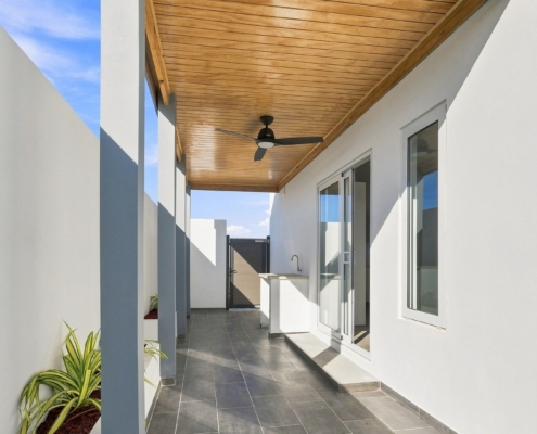 Reina Sophia Model Luca Unit 32 Covered Patio in Aruba Covered outdoor patio at Reina Sophia Model Luca Unit 32 in Aruba with a wood ceiling, ceiling fan, tiled floor, white walls, and sliding glass doors.