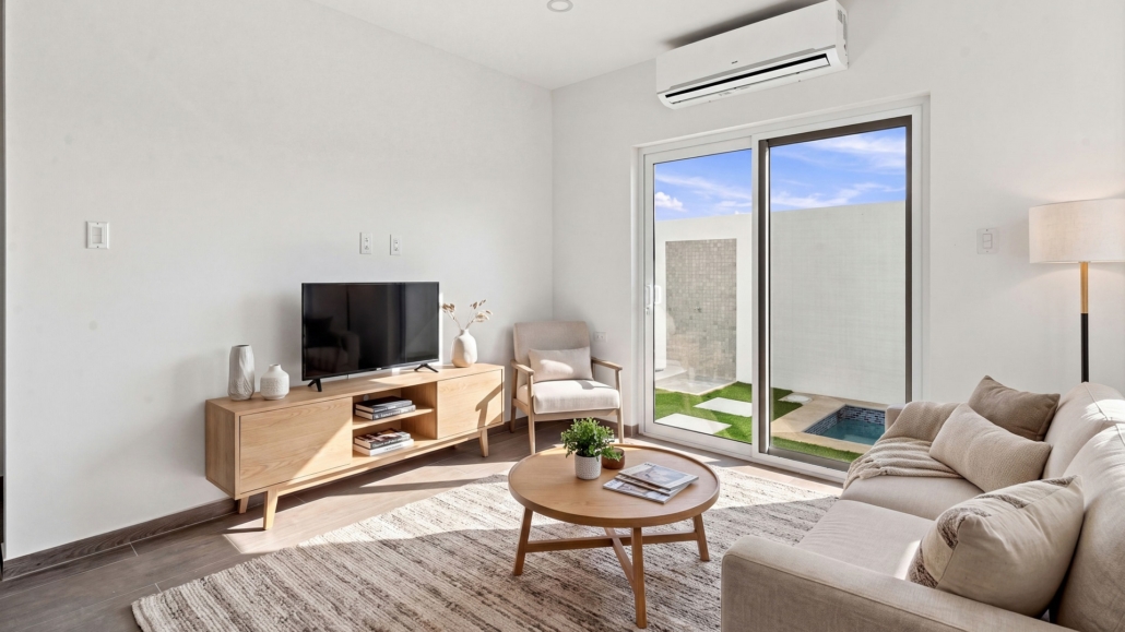 Staged living room at Reina Sophia Model Luca Unit 32 Aruba Staged Reina Sophia Model Luca Unit 32 living room in Aruba with a sofa, coffee table, television, armchair, rug, floor lamp, and sliding glass doors.