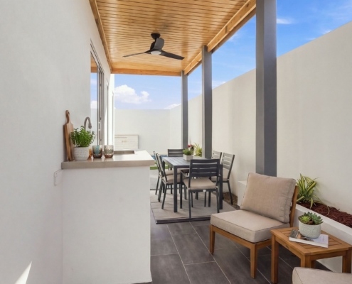 Reina Sophia Model Luca Unit 36 Outdoor Dining Patio in Aruba Covered outdoor dining area at Reina Sophia Model Luca Unit 36 in Aruba with a dining table and chairs, lounge chairs, a counter with sink, tiled floor, and wood ceiling.